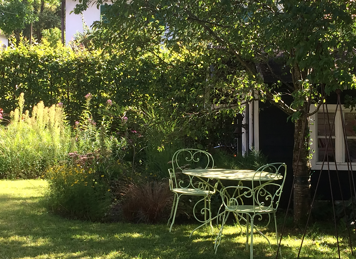 Geschützter Sitzplatz zwischen Obstbäumen und blühenden Stauden im Landgarten