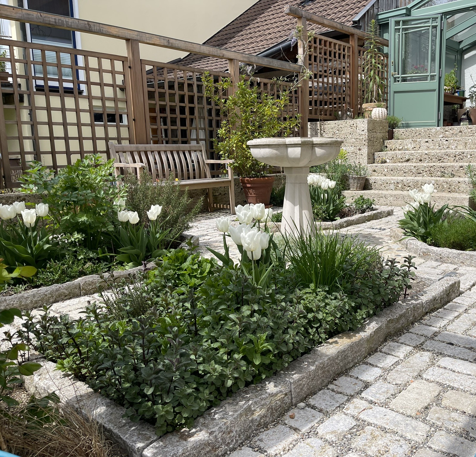 Brunnenraum zwischen Orangerie, Kräuterbeeten und Natursteintreppe