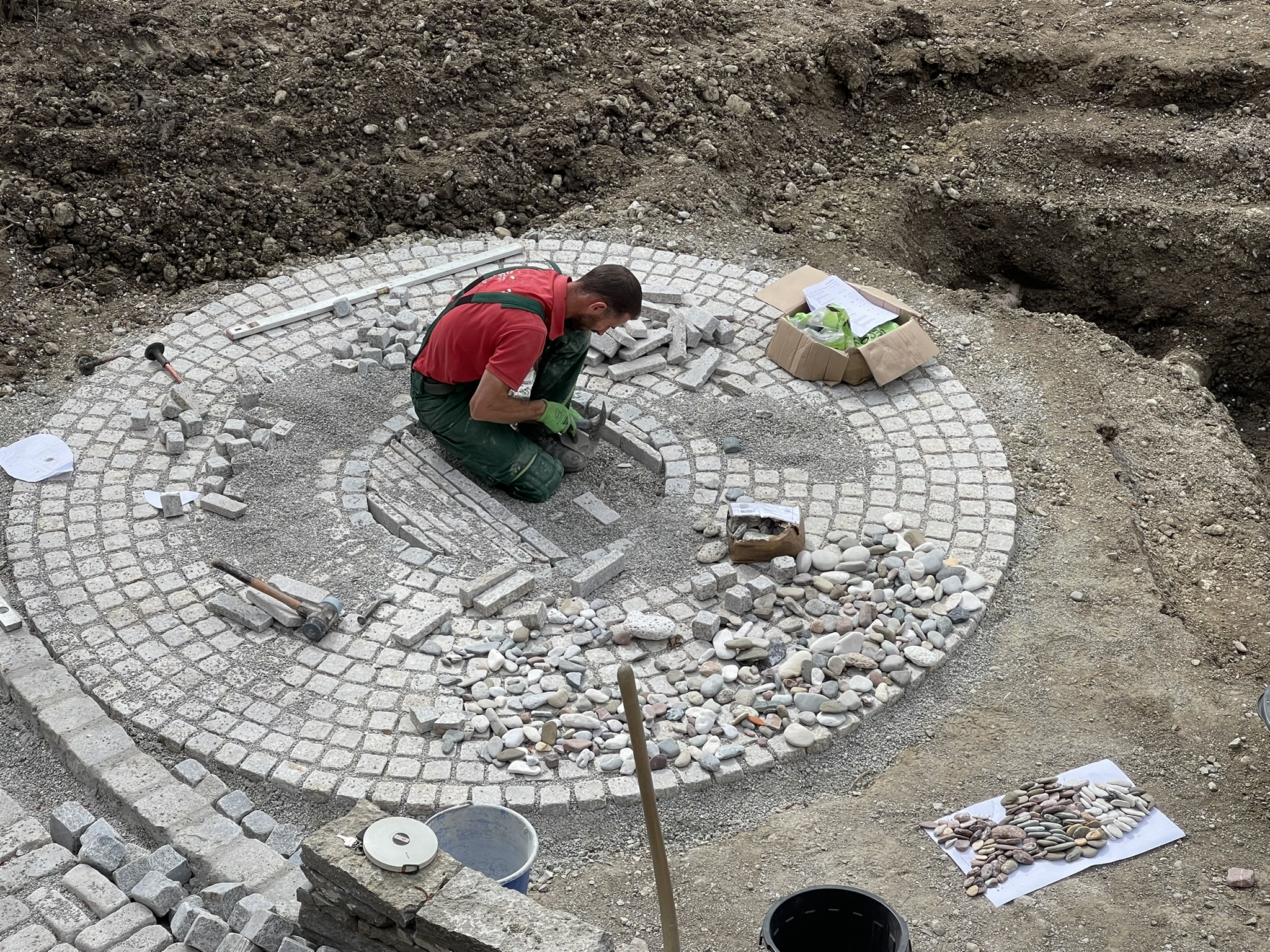 Handwerker bei der präzisen Ausführung des kreisförmigen Natursteinpflasters