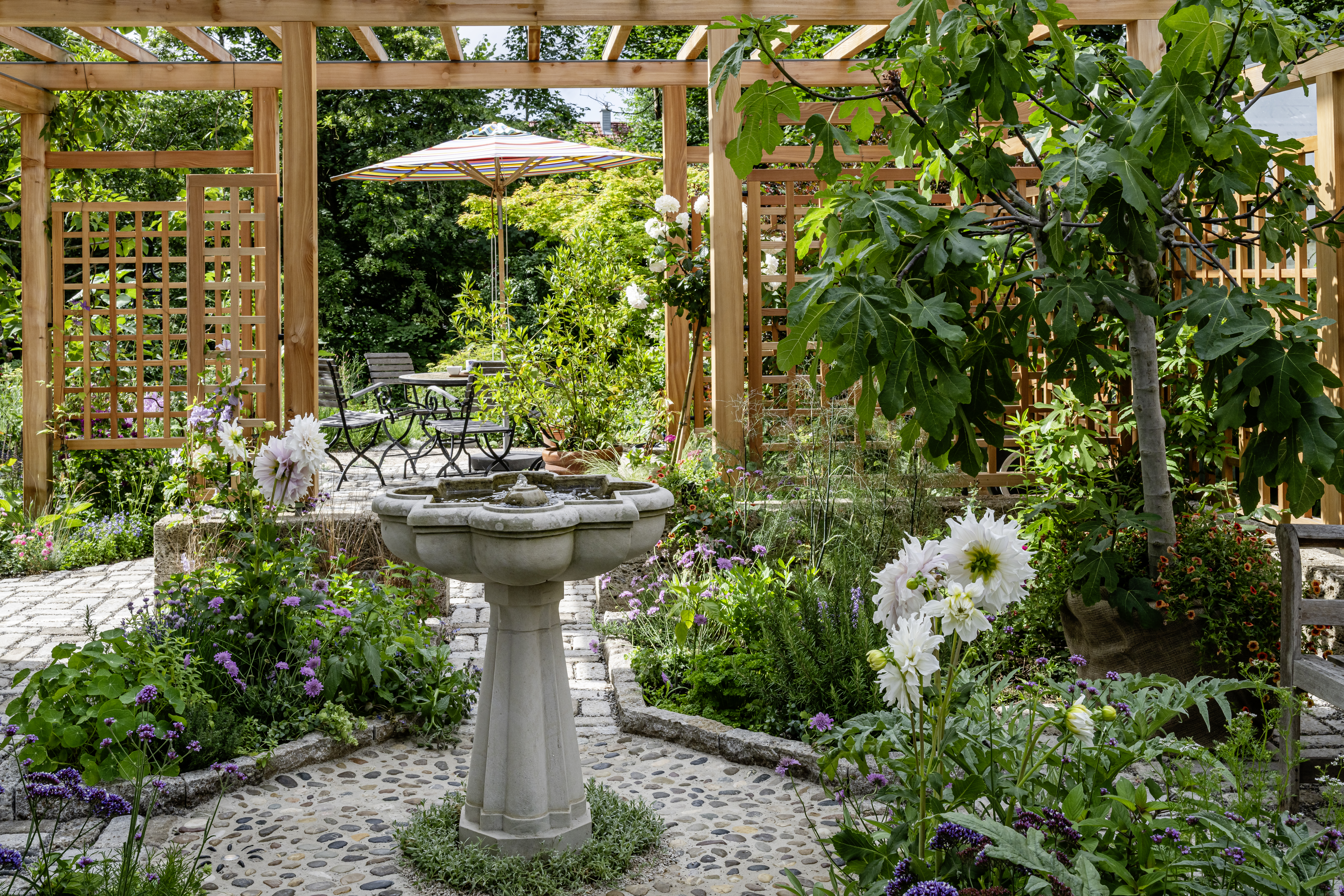 Warmer Gartenraum mit Brunnen und Pergola in Windach