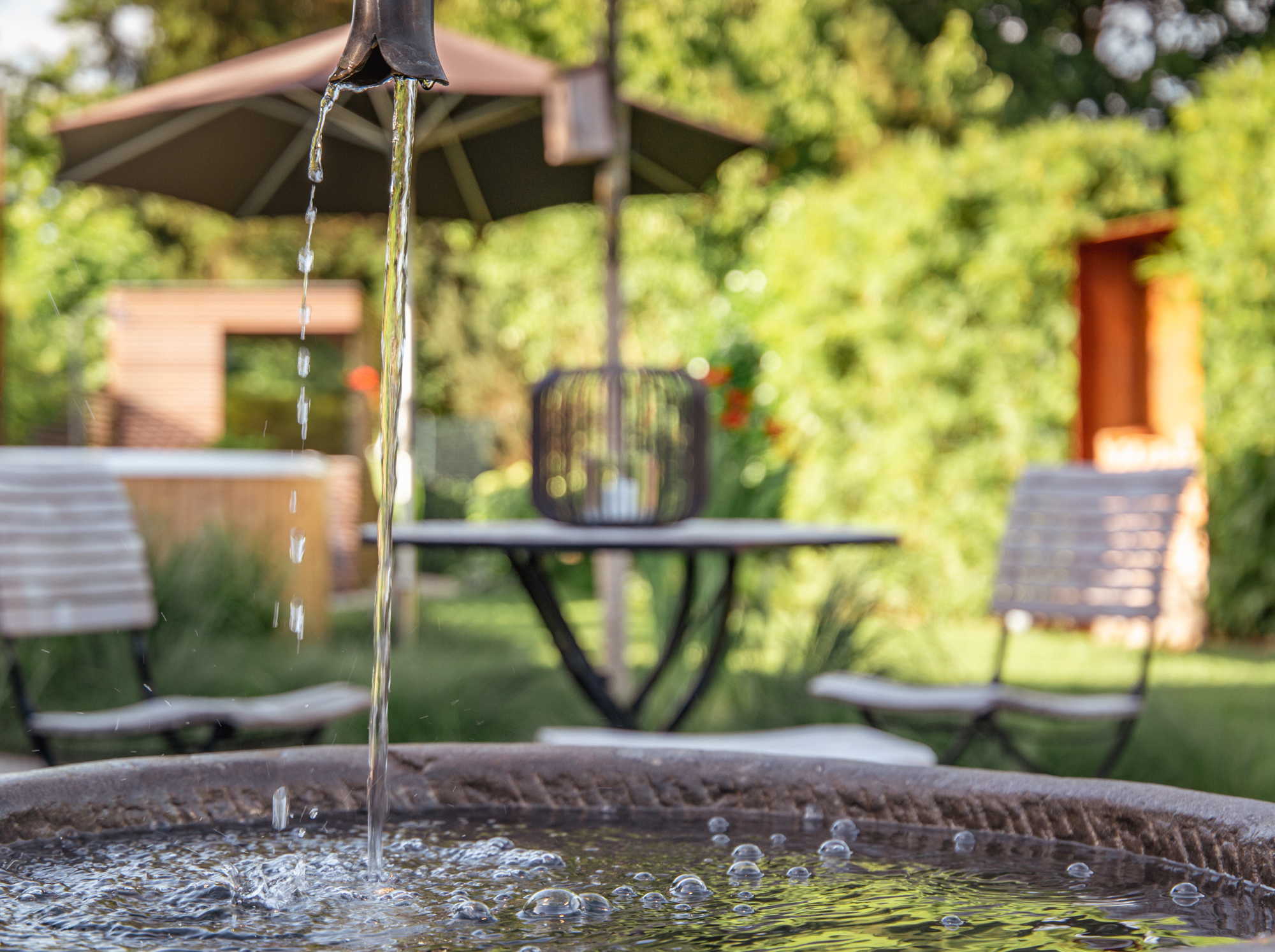 Fließendes Wasser am Steinbrunnen vor dem Sitzplatz im Garten Bayer